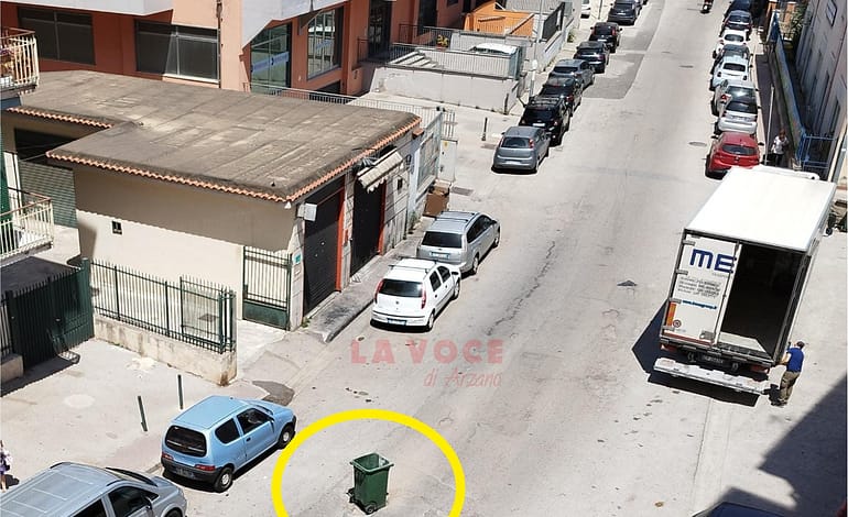 Via Ferrara, un cassonetto per segnalare una buca pericolosa